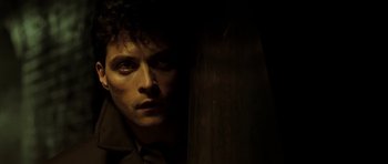 Movie still from “Dark City” (1998), directed by Alex Proyas – A person wearing a suit and tie; Close Up shot, Low angle