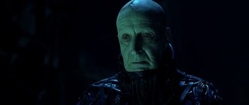 Movie still from “Dark City” (1998), directed by Alex Proyas – An old man with a bald head wearing a green costume; Close Up shot, Low angle