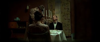 Movie still from “Dark City” (1998), directed by Alex Proyas – A man sitting at a dinner table with candles; Medium shot, Over the shoulder angle