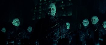 Movie still from “Dark City” (1998), directed by Alex Proyas – A group of people in a dark room; Medium shot, Low angle