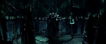 Movie still from “Dark City” (1998), directed by Alex Proyas – A group of people standing around in a dark room; Wide shot, High angle