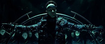 Movie still from “Dark City” (1998), directed by Alex Proyas – A man in a black outfit and some people; Medium shot, Low angle