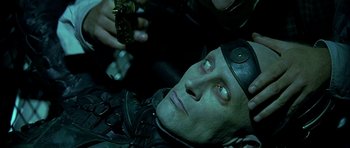 Movie still from “Dark City” (1998), directed by Alex Proyas – A person laying on the ground holding a gun; Close Up shot, Overhead angle
