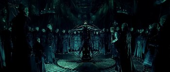 Movie still from “Dark City” (1998), directed by Alex Proyas – A group of people standing in a room; Wide shot, High angle