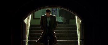 Movie still from “Dark City” (1998), directed by Alex Proyas – A man standing on some steps in the dark; Wide shot, Low angle