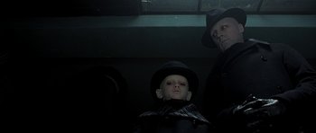 Movie still from “Dark City” (1998), directed by Alex Proyas – A man and a boy in a black hat and black coat; Close Up shot, Overhead angle
