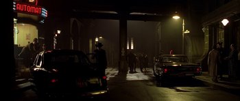 Movie still from “Dark City” (1998), directed by Alex Proyas – A group of people standing in the dark next to some cars; Wide shot, High angle