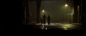 Movie still from “Dark City” (1998), directed by Alex Proyas – A group of people in a dark area with a lamp post in the background; Wide shot, Low angle