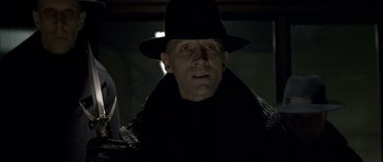 Movie still from “Dark City” (1998), directed by Alex Proyas – A person wearing a hat; Close Up shot, Low angle