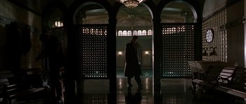 Movie still from “Dark City” (1998), directed by Alex Proyas – A man walking in the dark in front of an archway; Wide shot, Low angle