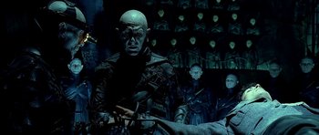 Movie still from “Dark City” (1998), directed by Alex Proyas – A group of people in a dark room; Medium shot, High angle