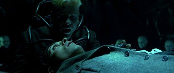Movie still from “Dark City” (1998), directed by Alex Proyas – A man laying on the ground with a woman in a dark room; Close Up shot, High angle