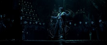 Movie still from “Dark City” (1998), directed by Alex Proyas – A man standing next to a wheel in a dark room; Wide shot, High angle