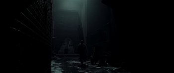 Movie still from “Dark City” (1998), directed by Alex Proyas – A man standing in a dark alley next to a bench; Extreme Wide shot, Low angle