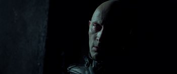 Movie still from “Dark City” (1998), directed by Alex Proyas – A man with bald head wearing a leather jacket; Close Up shot, Low angle