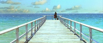 Movie still from “Dark City” (1998), directed by Alex Proyas – A person sitting on a pier looking out at the ocean; Extreme Wide shot, High angle