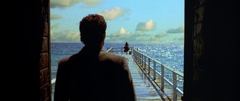 Movie still from “Dark City” (1998), directed by Alex Proyas – A man standing on a pier looking out at the ocean; Extreme Wide shot, Over the shoulder angle