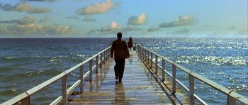 Movie still from “Dark City” (1998), directed by Alex Proyas – A man and a woman walking across a pier; Extreme Wide shot, High angle
