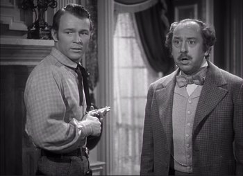 Movie still from “Dark Command” (1940), directed by Raoul Walsh – A man and a man standing next to each other in front of a window; Medium shot, Over the shoulder angle