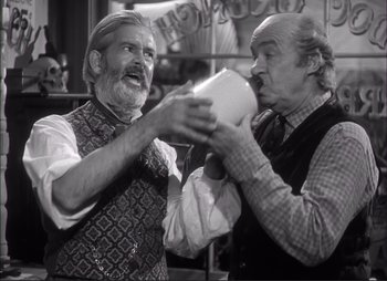 Movie still from “Dark Command” (1940), directed by Raoul Walsh – Two older men are holding papers and talking to each other; Medium shot, Low angle
