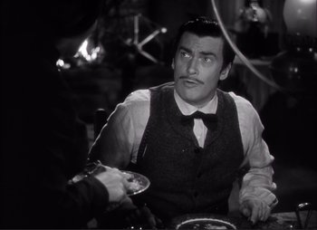 Movie still from “Dark Command” (1940), directed by Raoul Walsh – A black and white photo of a man sitting at a table; Medium shot, Over the shoulder angle