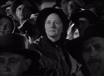 Movie still from “Dark Command” (1940), directed by Raoul Walsh – A woman in a crowd of people wearing hats; Medium shot, Low angle