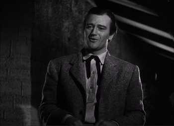 Movie still from “Dark Command” (1940), directed by Raoul Walsh – A black and white photo of a man in a suit and tie; Medium shot, Low angle