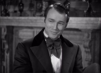 Movie still from “Dark Command” (1940), directed by Raoul Walsh – A man wearing a suit and a bow tie; Close Up shot, Over the shoulder angle