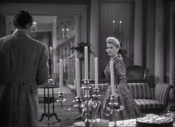 Movie still from “Dark Command” (1940), directed by Raoul Walsh – An old photo of a man and a woman standing in front of candles; Medium shot, Over the shoulder angle