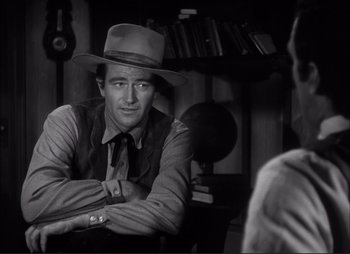 Movie still from “Dark Command” (1940), directed by Raoul Walsh – A black and white photo of a man wearing a hat; Medium shot, Over the shoulder angle