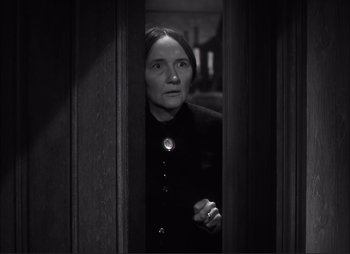 Movie still from “Dark Command” (1940), directed by Raoul Walsh – A woman standing in a doorway looking at the camera; Medium shot, High angle