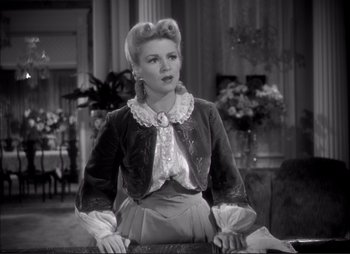 Movie still from “Dark Command” (1940), directed by Raoul Walsh – A black and white photo of a woman in a short dress; Medium shot, Over the shoulder angle