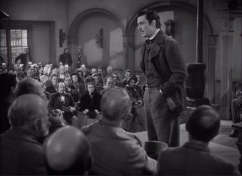 Movie still from “Dark Command” (1940), directed by Raoul Walsh – A man standing in front of a crowd of people; Wide shot, Over the shoulder angle