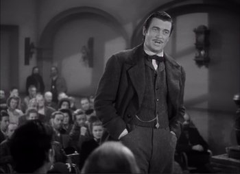 Movie still from “Dark Command” (1940), directed by Raoul Walsh – A black and white photo of a man standing in front of an audience; Medium shot, Low angle