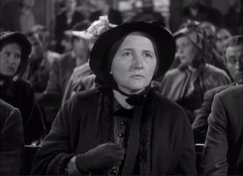 Movie still from “Dark Command” (1940), directed by Raoul Walsh – An older woman wearing a black hat and a black coat; Close Up shot, Over the shoulder angle