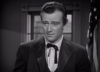 Movie still from “Dark Command” (1940), directed by Raoul Walsh – A black and white photo of a man wearing a suit and bow tie; Close Up shot, Over the shoulder angle