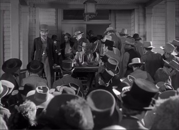Movie still from “Dark Command” (1940), directed by Raoul Walsh – A group of people gathered around a table; Wide shot, High angle