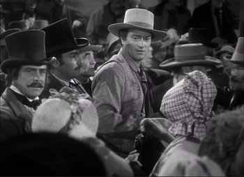 Movie still from “Dark Command” (1940), directed by Raoul Walsh – A group of people wearing hats in a room; Medium shot, Over the shoulder angle