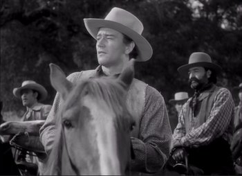 Movie still from “Dark Command” (1940), directed by Raoul Walsh – A man wearing a cowboy hat standing next to a horse; Medium shot, Low angle
