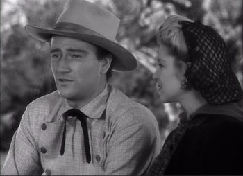 Movie still from “Dark Command” (1940), directed by Raoul Walsh – A man and a woman wearing hats and a tie; Medium shot, Low angle