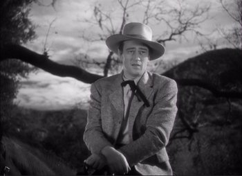 Movie still from “Dark Command” (1940), directed by Raoul Walsh – A black and white photo of a man in a suit and hat; Medium shot, Low angle