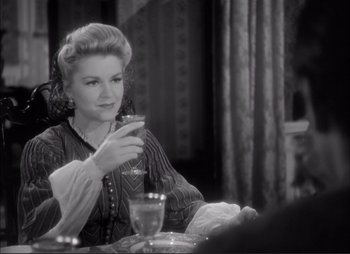 Movie still from “Dark Command” (1940), directed by Raoul Walsh – A woman sitting at a table with a glass of wine; Medium shot, Over the shoulder angle