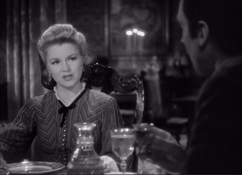 Movie still from “Dark Command” (1940), directed by Raoul Walsh – A woman sitting at a dinner table with a man; Medium shot, Over the shoulder angle