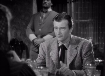 Movie still from “Dark Command” (1940), directed by Raoul Walsh – A black and white photo of a man sitting at a table; Medium shot, Over the shoulder angle
