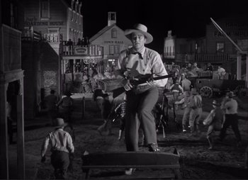 Movie still from “Dark Command” (1940), directed by Raoul Walsh – A man in a cowboy hat holding a rifle; Wide shot, Low angle
