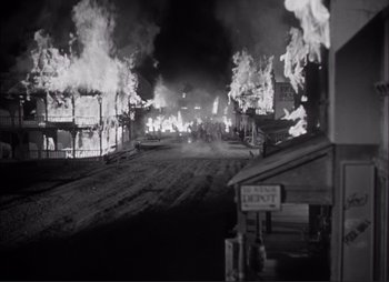 Movie still from “Dark Command” (1940), directed by Raoul Walsh – An old photo of a street with burning buildings; Extreme Wide shot, High angle