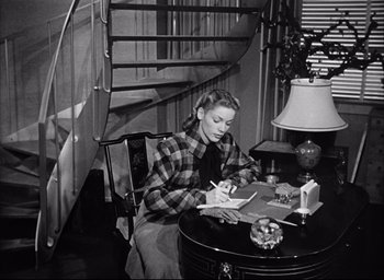 Movie still from “Dark Passage” (1947), directed by Delmer Daves – A woman sitting at a table writing on a piece of paper; Medium shot, High angle