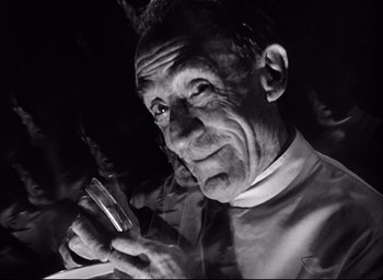 Movie still from “Dark Passage” (1947), directed by Delmer Daves – An older man holding a cigarette and a drink; Close Up shot, Low angle