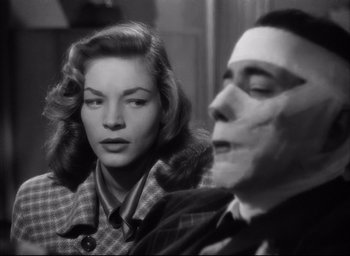 Movie still from “Dark Passage” (1947), directed by Delmer Daves – A man and a woman sitting next to each other in a room; Close Up shot, Over the shoulder angle