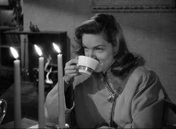 Movie still from “Dark Passage” (1947), directed by Delmer Daves – A black and white photo of a woman drinking a cup; Medium shot, High angle